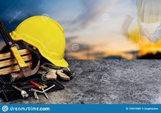 a hard hat, tools and other construction equipment on a concrete surface with blurry background