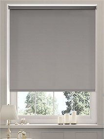 a living room with a window covered in gray roller shades next to a table and lamp