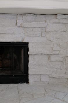 a fire place in the middle of a room with stone walls and a window above it