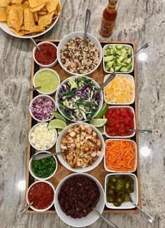 a table topped with bowls filled with different types of food next to plates of vegetables and dips