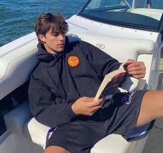 a man is sitting on the back of a boat reading a paper while wearing shorts