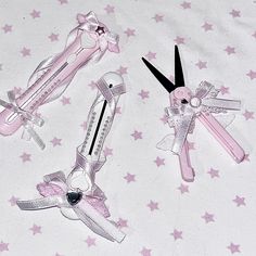 three pink scissors laying on top of a white sheet with stars around them and one is cut into the shape of an angel