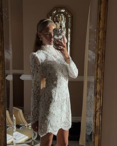 a woman taking a selfie in front of a mirror wearing a white lace dress