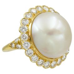 Van Cleef & Arpels Pearl And Diamond Ring, Crafted In 18k Yellow Gold. The center of this statement ring features oval shaped cultured pearl set in the center, measuring approximately 17.4 X 14.5mm. The pearl has a creamy white color with soft rose overtones and good luster. Surrounded by a halo consisting of approximately 2.25 carats of round brilliant cut diamond, color colorless, clarity VS. The ring is in size 5.75 with hinged shank. Inscribed: Van Cleef & Arpels, Mxxxx Stamped with French h Van Cleef & Arpels, Van Cleef And Arpels, Pearl And Diamond Ring, Gold Cocktail Ring, Gold Cocktail, Soft Rose, 18k Gold Ring, Pearl Set, Van Cleef Arpels