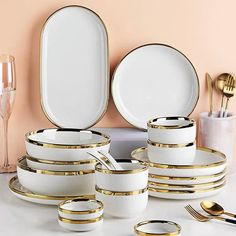 a table topped with plates and silverware on top of a white counter next to a pink wall