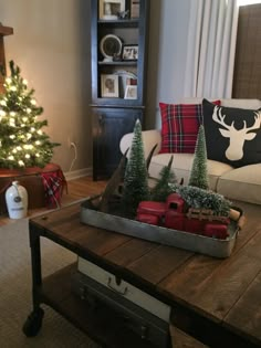 a living room filled with furniture and a christmas tree on top of a coffee table