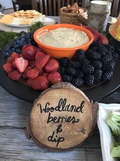 a plate with berries, strawberries and dip on it next to other food items