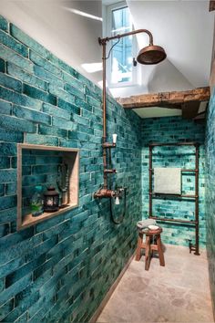 a bathroom with blue glass tiles on the wall and shelves in the shower area, along with a wooden stool