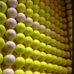 many tennis balls are stacked on top of each other in a racket room with yellow and white walls