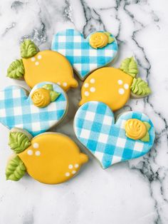 four decorated cookies sitting on top of a marble counter next to blue and white checkered cloth