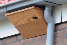 a bird house attached to the side of a brick building with a metal gutter