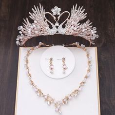 a tiara and jewelry set sitting on top of a white box next to a pair of earrings