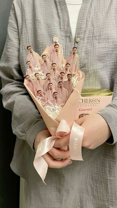 a person holding a bunch of paper dolls in their hands with ribbons around them and the faces of people on them