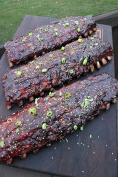 ribs covered in bbq sauce and garnished with green onions on a cutting board