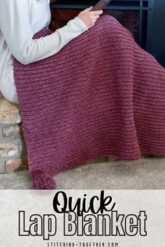 a woman is sitting on the floor with a knitted blanket in front of her