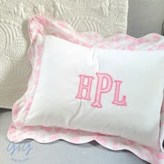 an embroidered pillow with the letters apl on it and pink trim around the edges