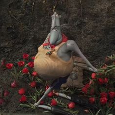 an elephant statue sitting on top of a pile of flowers next to a dead animal