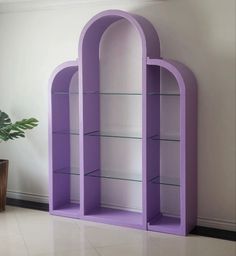 a purple bookcase sitting on top of a white floor next to a potted plant