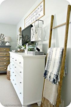 a white dresser sitting in a bedroom next to a wooden ladder