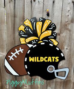 a wooden sign that says wildcatss and a football with a flower on it hanging from a fence