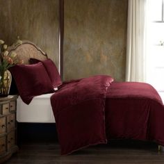 a bed with red sheets and pillows in a bedroom