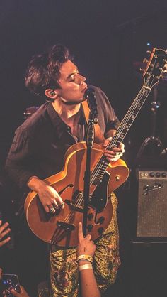 a man holding a guitar in front of a microphone