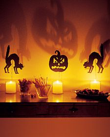 halloween decorations are lit up on a shelf with candles and pumpkins in the background