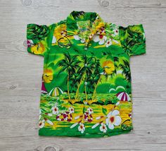 "Vintage Hawaiian Shirt kids Cotton Colorful Tropical Summer Short Sleev Shirt Toddler Boys Camp Collar Button Up short sleeve shirt Lightweight and comfortable. * Size on label: NA Please see measurements Approx fit 3 years * Cotton. * Good used vintage condition. Measurements: Shoulder to shoulder 12\"/ 31 cm Pit to pit 14.5\"/ 37 cm Length: 20 / 51 cm ☆ SHIP WORLDWIDE ☆ I ship from Latvia EU worldwide. Estimated delivery time to: European Union 5 - 7 Business days; USA 2 - 3 weeks; Worldwide Green Summer T-shirt With Buttons, Green Short Sleeve Summer Shirt, Green Short Sleeve Shirt With Buttons For Summer, Green Collared Short Sleeve Beach Shirt, Boys Camp, Tropical Shirt, Vintage Hawaii, Photo To Cartoon, Vintage Hawaiian Shirts