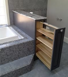 a bath tub sitting next to a wooden cabinet in a room with tile floors and walls