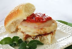 a sandwich with meat and sauce is on a white plate next to a green leafy garnish