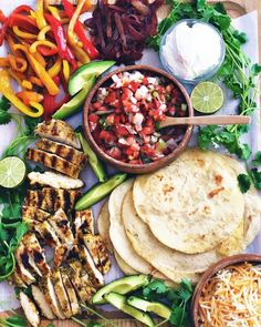 a platter with chicken, tortillas, peppers, and other food items