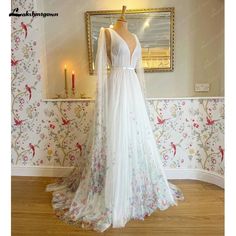 a white wedding dress on display in front of a wallpapered room with candles