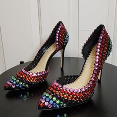 a pair of black high heeled shoes with multi - colored sequins on them