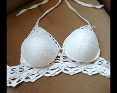 two white bras with crocheted lace on them are laying on a cardboard box