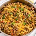 a casserole dish with noodles and meat in it on a white tablecloth