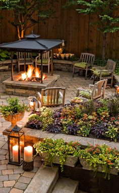 a fire pit surrounded by chairs and tables with lit candles in the middle of it