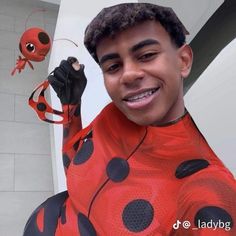 a man in a ladybug costume is smiling and holding up his hand to the camera