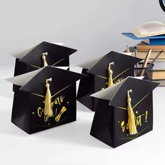 four graduation caps with tassels on them are sitting next to books and a clock