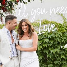 a man and woman standing next to each other in front of a sign that says all you need is love