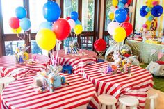 a table with red, white and blue striped cloths on it is set up for a circus themed birthday party