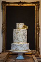 a white and gold wedding cake sitting on top of a table next to a framed photo