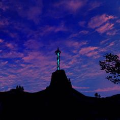 the silhouette of a statue against a purple and blue sky