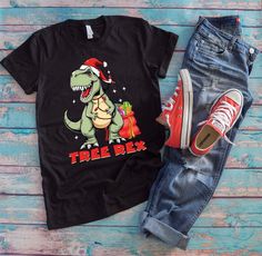 Get ready for a roaring holiday with this kds Christmas dinosaur shirt! Perfect for dino lovers, paleontologist or boys who love dinosaurs.  KIDS SIZES AND HOODIES AVAILABLE! FOR CUSTOM ORDER, PLEASE SEND US A MESSAGE! Inspired by the everyday joys we bring colors into your life by emphasizing everything that matters to you! Whether it is your birthday, anniversary or a special holiday celebration, we recognize how special these events are to you and want you to know that having the privilege to Dino Saurus, Tree Rex, Christmas Dinosaur, Slim Neck, Christmas Party Gift, Dinosaur Shirt, Dinosaur Gifts, Boy Shirt, Funny Christmas Shirts