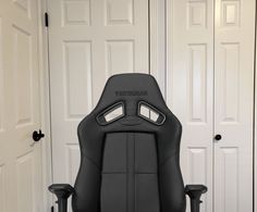 a black office chair sitting in front of two white closet doors, with the words vertgebran on it