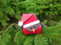 an origami bird with a santa hat on it's head sitting in a pine tree