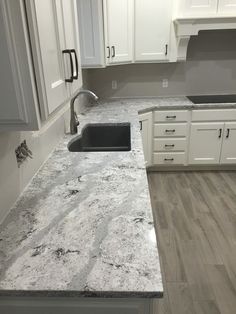 a kitchen with marble counter tops and white cabinets