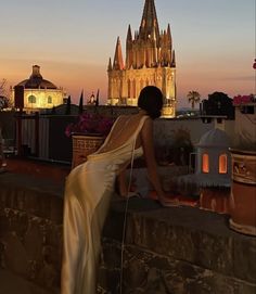 a woman standing on top of a roof next to a tall building with a spire