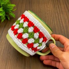 a hand is holding a crocheted coffee cup