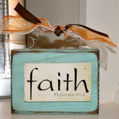 a wooden block with the word faith on it and two ribbons hanging from it's sides