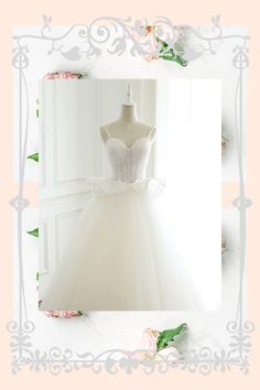 a white wedding dress on display in front of a flowery background with pink roses